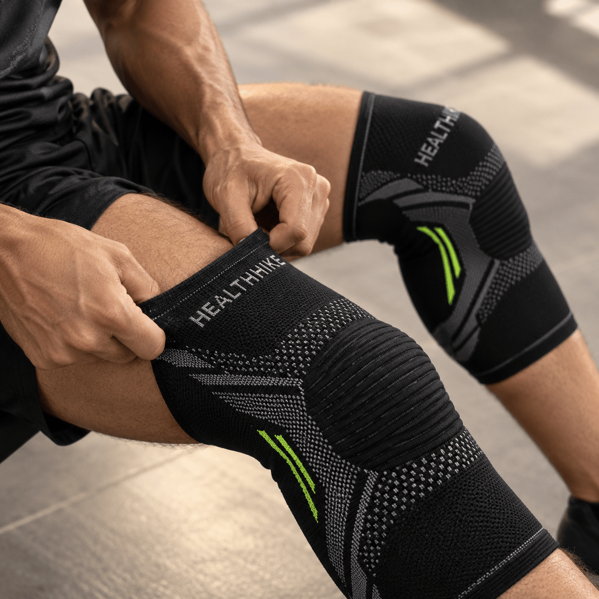 Athlete adjusting a HealthHike Black Knee Support Sleeve while seated, showing its stretchable knitted fit.